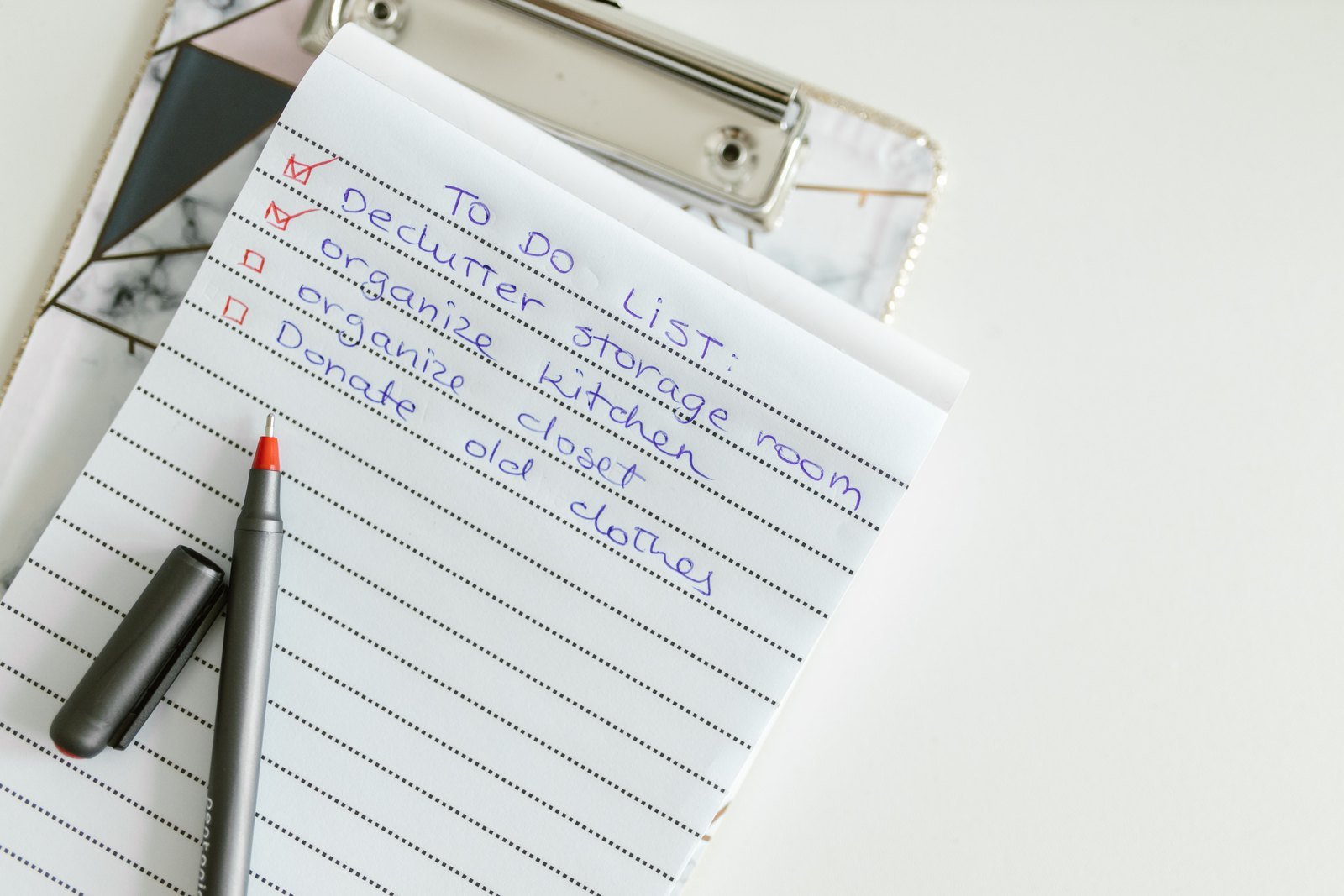 A handwritten checklist on a clipboard, with a pen resting on the page.