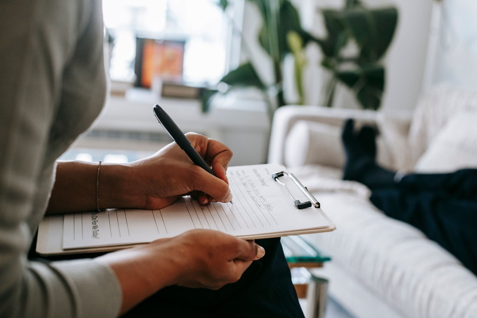A parent sitting alone in a clinic waiting room with a folder of papers held on their lap